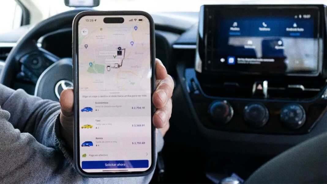 Taxi circulando por las calles de Rosario, con un teléfono mostrando una aplicación de viajes.