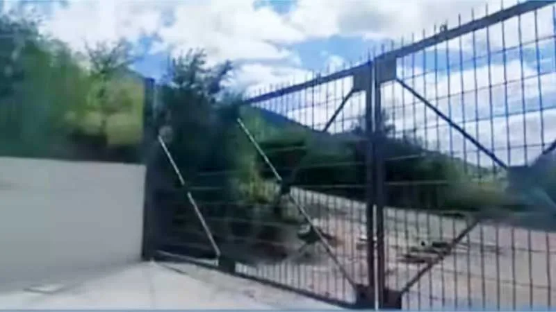 Fotografía representativa de un camino de tierra en una zona serrana, con un portón cerrado que bloquea el paso.