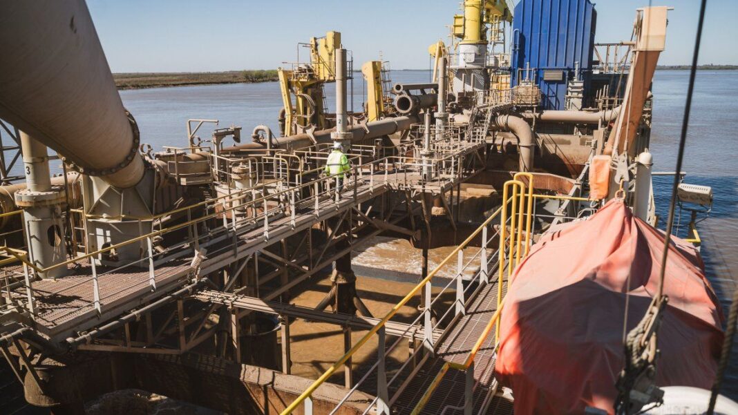 Logotipo de Jan De Nul junto a una ilustración de una draga en un río