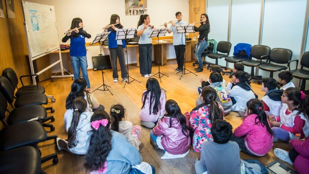 Alumnos de la Escuela Orquesta Barrio Ludueña tocando instrumentos de cuerda en un concierto